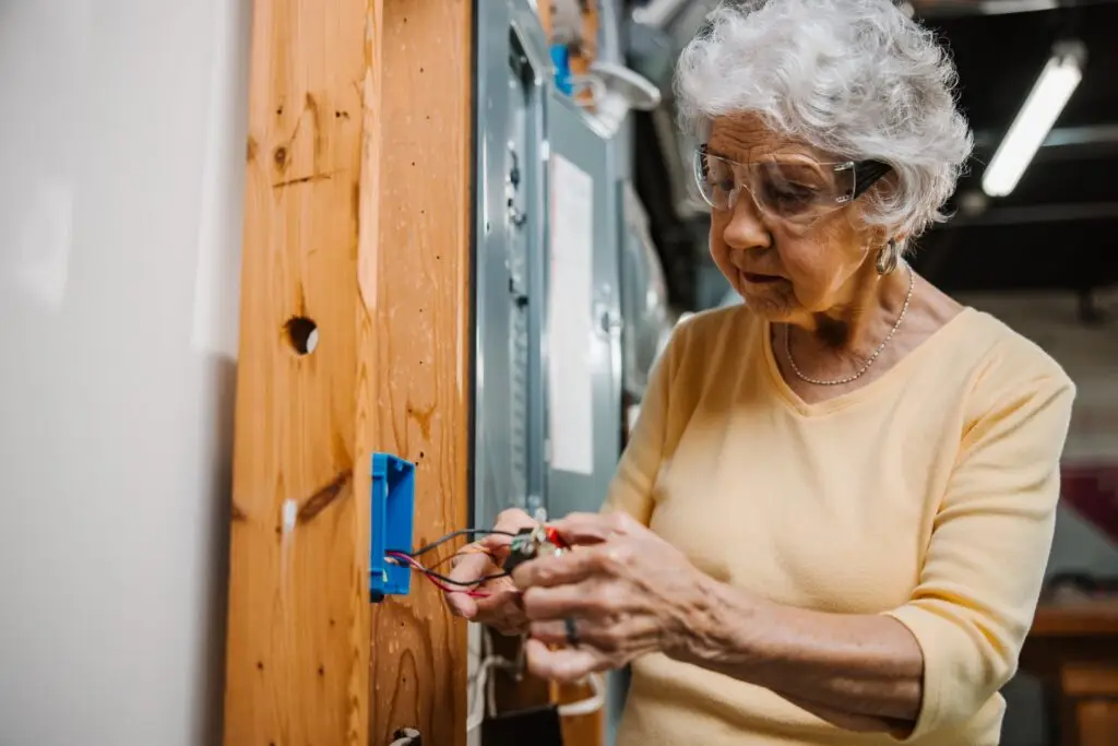 Woman wearing safety glasses and working on an electrical outlet.