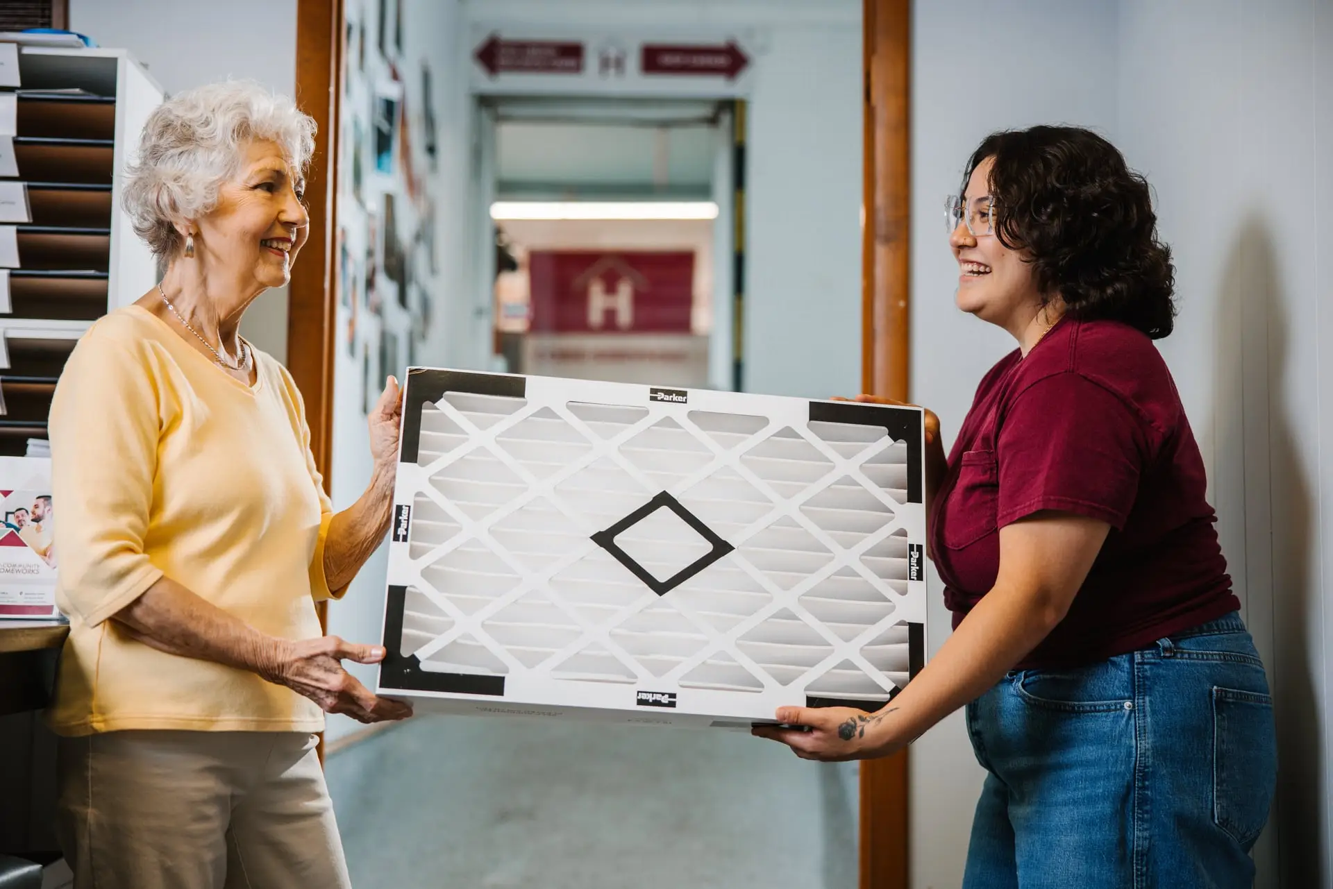 Two women carrying an air filter.